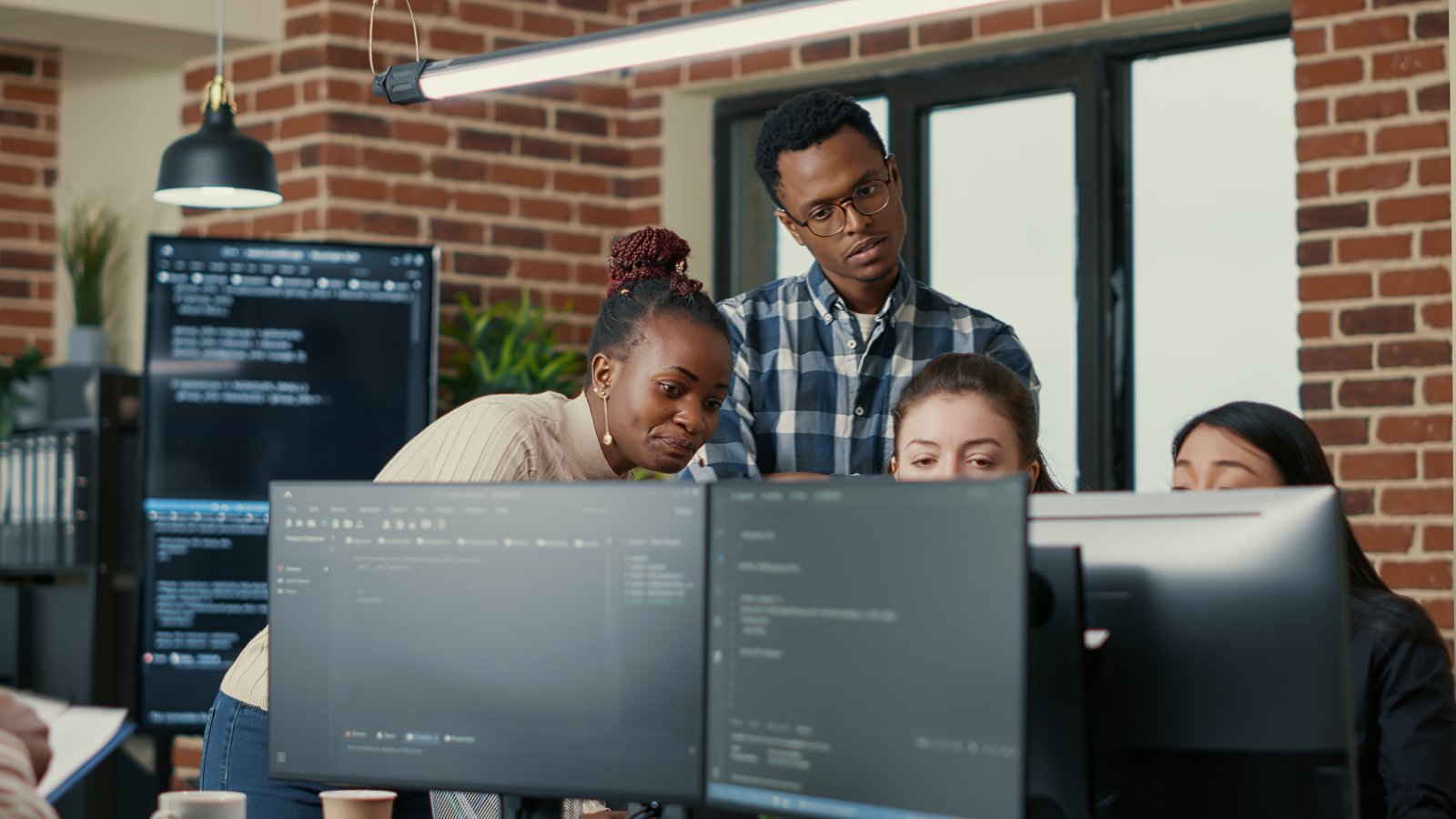 Developers collaborating around computer screens with code